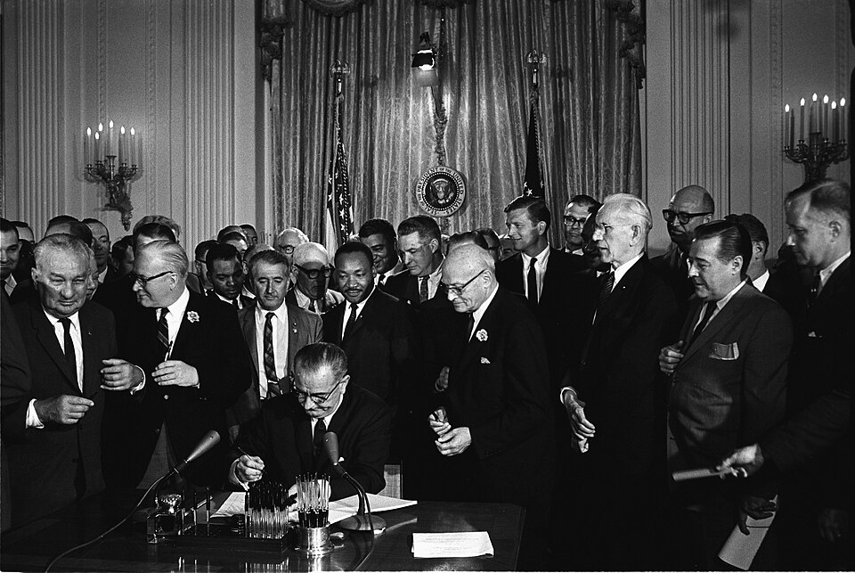 Präsident Johnson unterzeichnet den Civil Rights Act, im Hintergrund Martin Luther King